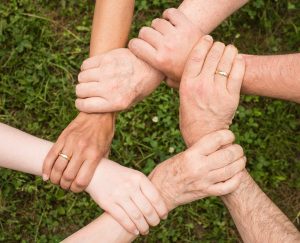 People linking hands together in a trust circle.