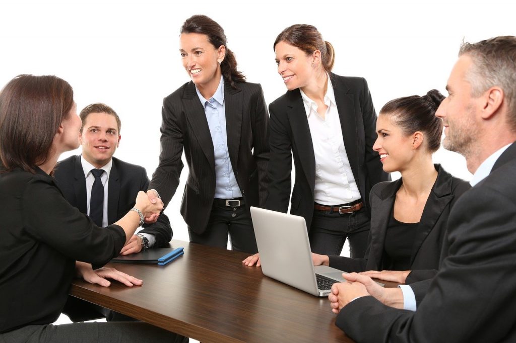 People around a networking table shaking hands.