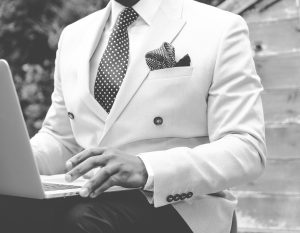 A man well dressed in a suit at his laptop.