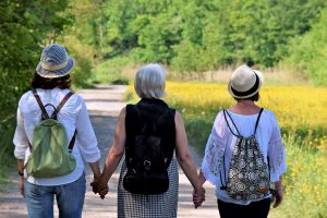 Three woman walking all holding hands together.