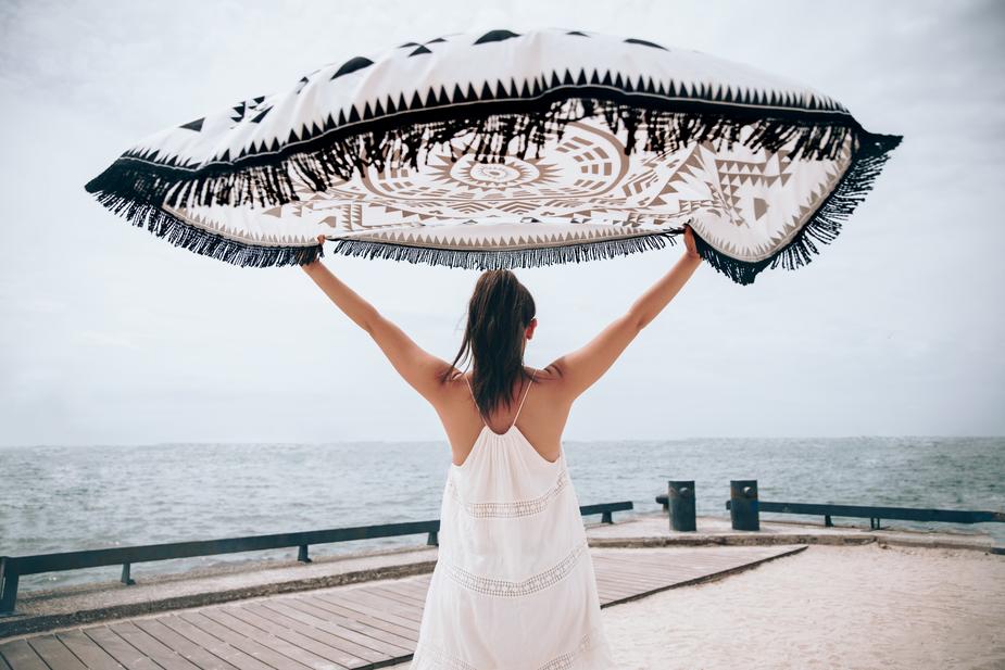 A woman holding a blanket above her head showing joy.