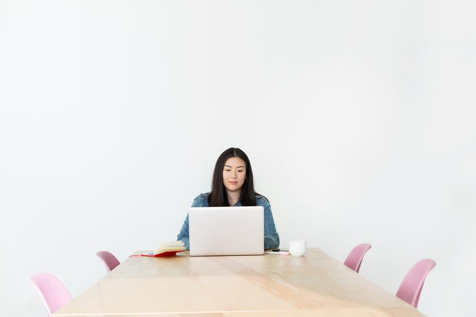 A woman sitting in a board room on her laptop.