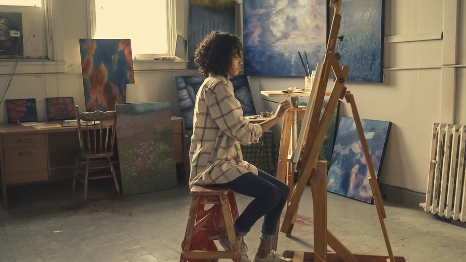 A woman painting at her easel.