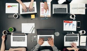 People working at a desk on their laptops and business.